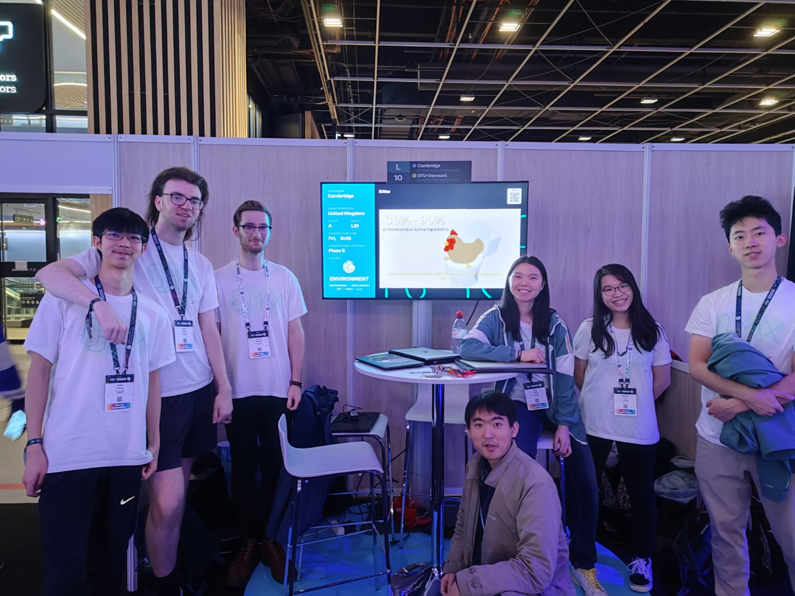 The team at their Jamboree team booth with a screen playing their promotion video