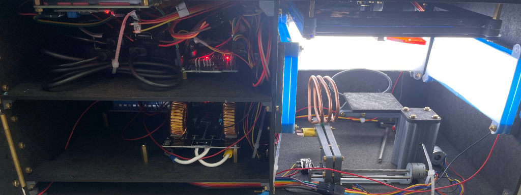 A photo of the inside of the MaGenTa hardware. On the right is an illuminated chamber with a platform for specimens and a coil. On the right are a series of wiring, microprocessor boards and coils.