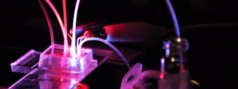 A microfluidics platform illuminated with coloured lights.
