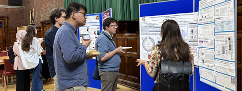 A group of researchers chat in front of a poster board