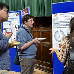 A group of researchers chat in front of a poster board