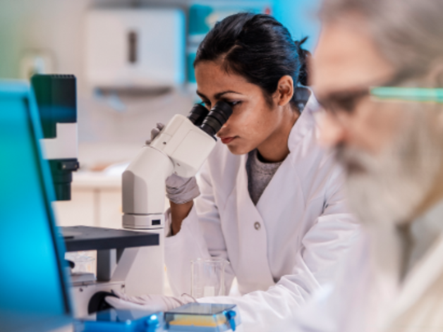 Photo of female scientist looking into a microscope