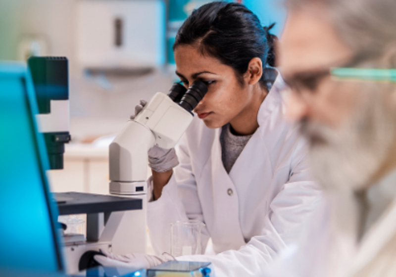 Photo of female scientist looking into a microscope