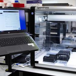 Photo of an Opentron lab automation robot and and laptop used for coding it